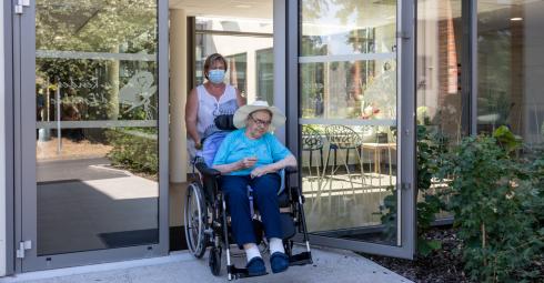 Une personne âgée dans un fauteuil roulant avec une aidante.